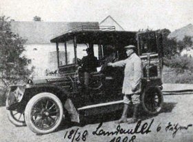 Eine historische Aufnahme des ersten Autos der Verwaltung des Landkreises Sankt Wendel von 1908; vor dem Auto steht der Fahrer.