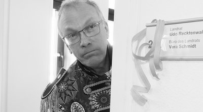 Landrat Udo Recktenwald steht an einer Tür und blickt traurig